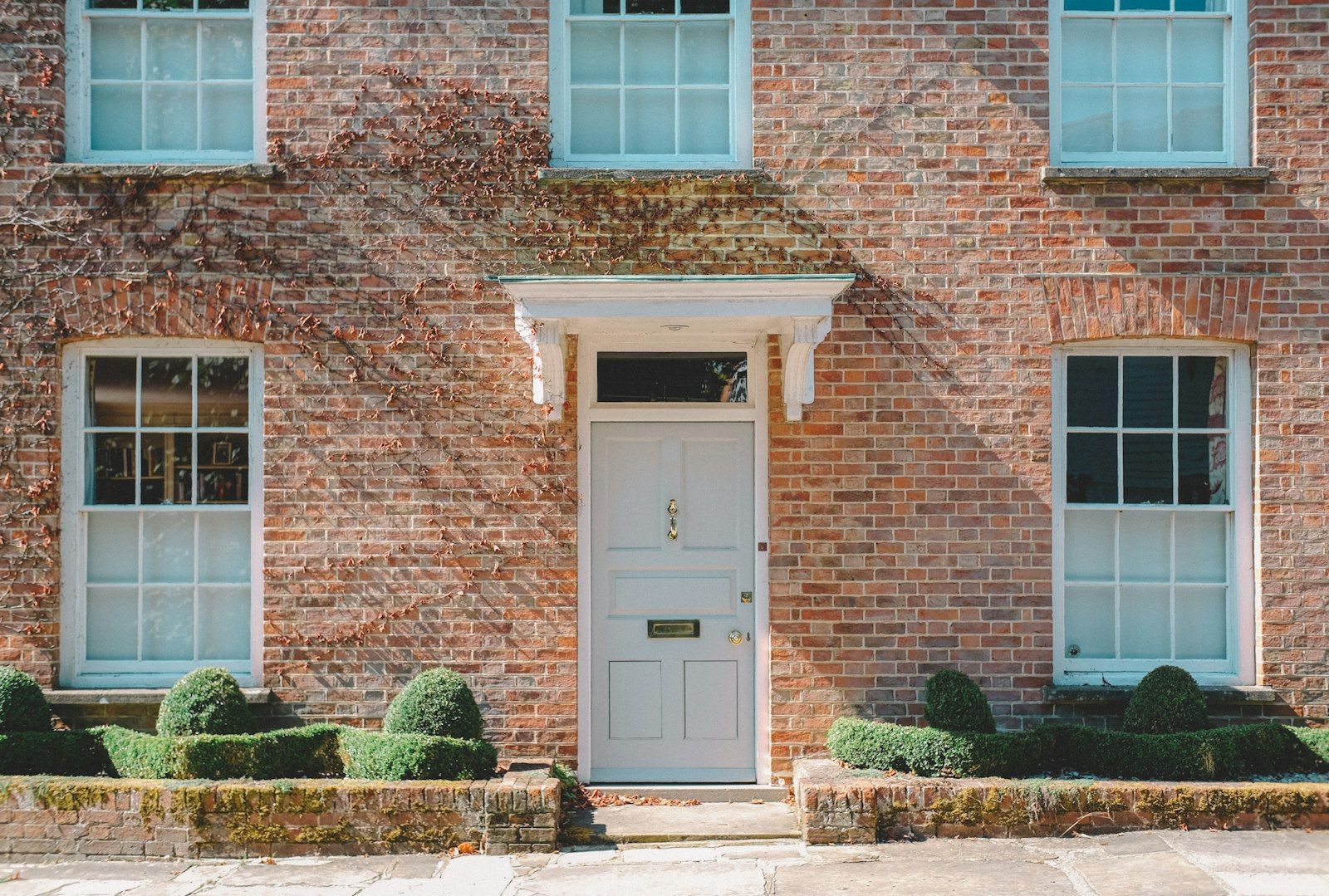 A brick house with sash windows and a pale front door