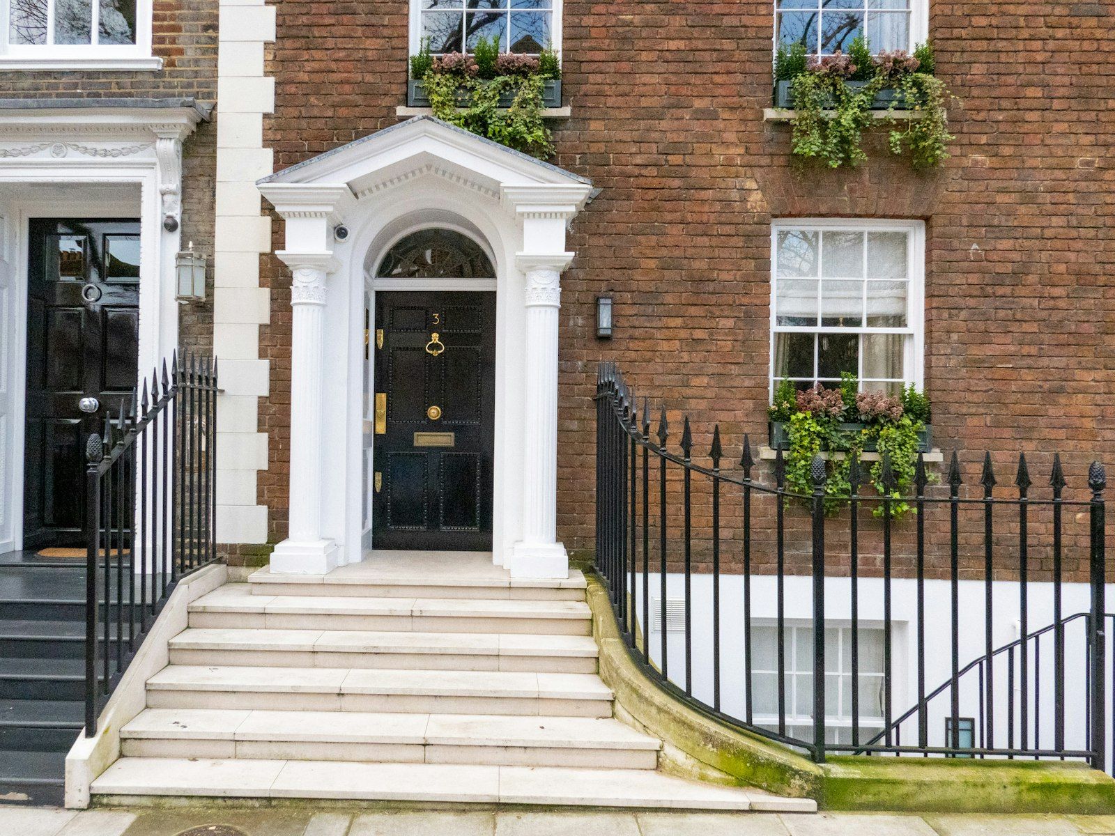 The black front door and iron railings of a Georgian townhouse